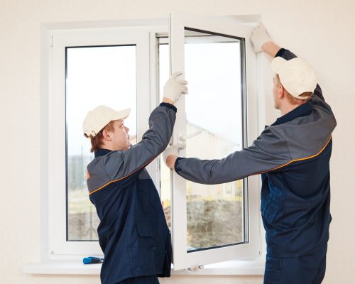 construction workers glaziers installing glass window indoor